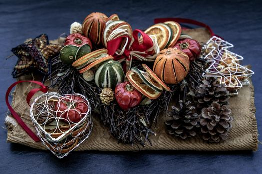 Christmas decoration. Twigs christmas tree, brown natural pine cones and variety of fruits on burlap fabric background. Oblique view from the top.