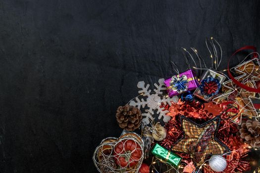 Christmas decoration. Twigs christmas tree, brown natural pine cones and and Xmas deer with variety of fruits on dark background. Top view, copy space.