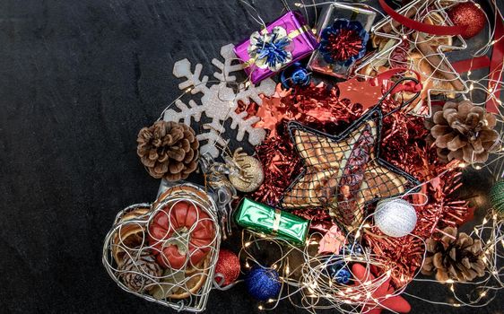 Christmas decoration. Twigs christmas tree, brown natural pine cones and and Xmas deer with variety of fruits on dark background. Top view, copy space.