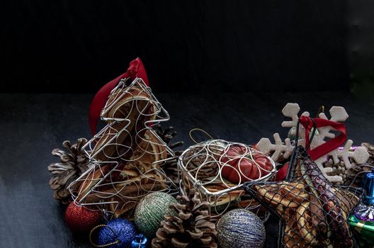 Christmas decoration. Twigs christmas tree, brown natural pine cones and and Xmas deer with variety of fruits on dark background. Oblique view from the top, copy space.