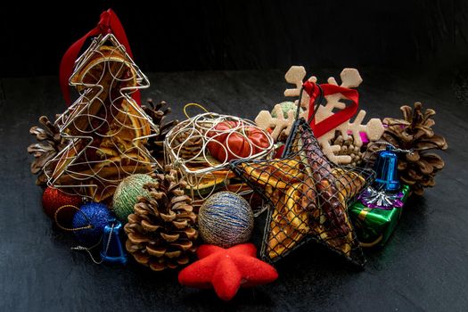 Christmas decoration. Twigs christmas tree, brown natural pine cones and and Xmas deer with variety of fruits on dark background. Oblique view from the top, copy space.
