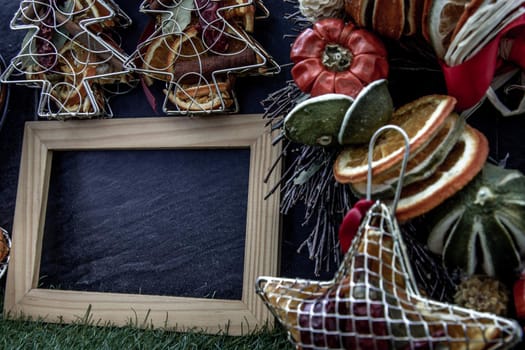 Christmas decoration, Brown natural pine cones and variety of fruits with Empty wooden frame for work about design element on lawn and dark background, Copy Space.