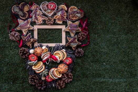 Christmas decoration, Brown natural pine cones and variety of fruits with Empty wooden frame for work about design element on lawn background, Copy Space.