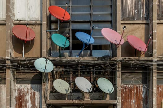 Bangkok, Thailand - 07 Feb 2020 : Many satellite dishes mounted to the outside wall of a residential building. Selective focus.