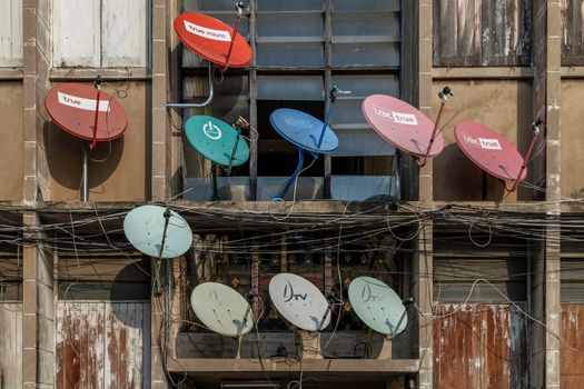 Bangkok, thailand - Feb 07, 2020 : Many satellite dishes mounted to the outside wall of a residential building. Selective focus.