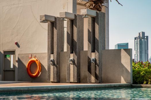 Outdoor and Poolside shower with skyscrapers on background. Showering before entering the swimming pool.