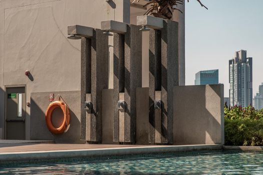 Outdoor and Poolside shower with skyscrapers on background. Showering before entering the swimming pool.