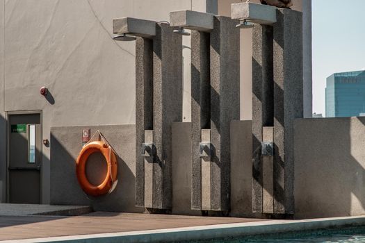 Outdoor and Poolside shower with skyscrapers on background. Showering before entering the swimming pool.