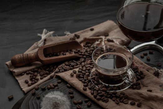 Coffee style, Cup of coffee and coffee beans roating with old wooden scoop and coffee beans around on the wooden and dark stone background. Oblique view from the top with copy space for your text.