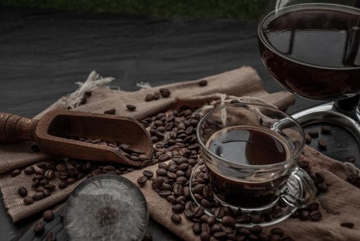 Coffee style, Cup of coffee and coffee beans roating with old wooden scoop and coffee beans around on the wooden and dark stone background. Oblique view from the top with copy space for your text, Selective focus.