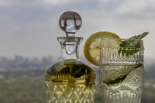 Cold water with lemon, kaffir lime, cucumber and mint leave on the table in front of sky background. Summer time, Healthy drink, vegetable juice, Selective Focus.