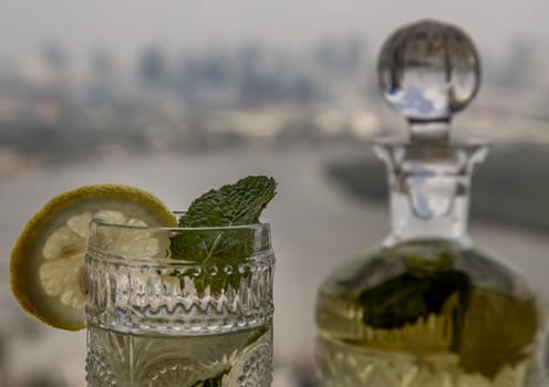 Cold water with lemon, kaffir lime, cucumber and mint leave on the table in front of sky background. Summer time, Healthy drink, vegetable juice, Selective Focus.