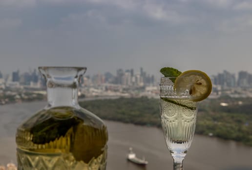 Cold water with lemon, kaffir lime, cucumber and mint leave on the table in front of sky background. Summer time, Healthy drink, vegetable juice, Selective Focus.