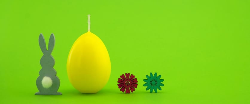 Minimalistic style Easter card with yellow egg shaped candle over a green background with free copy space for text