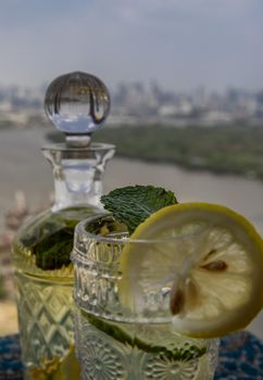 Cold water with lemon, kaffir lime, cucumber and mint leave on the table in front of sky background. Summer time, Healthy drink, vegetable juice, Selective Focus.
