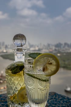Cold water with lemon, kaffir lime, cucumber and mint leave on the table in front of sky background. Summer time, Healthy drink, vegetable juice, Selective Focus.