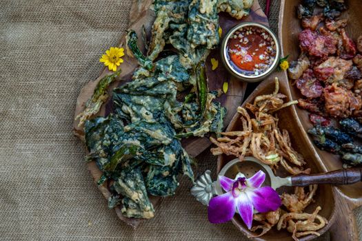 Close-up of Crispy Flowers, Crispy Herbs and Crispy Vegetables served  with Sweet sauce in a Wooden tray, copy space.