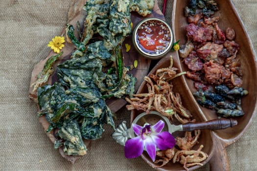 Close-up of Crispy Flowers, Crispy Herbs and Crispy Vegetables served  with Sweet sauce in a Wooden tray, copy space.