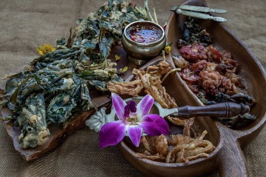 Crispy Flowers, Crispy Herbs and Crispy Vegetables served  with Sweet sauce in a Wooden tray, Oblique view from the top, copy space.