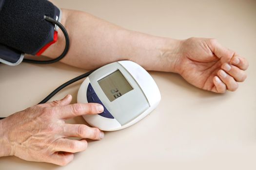 Blood pressure checks the man tonometer.Hands and the device lie on a light table.