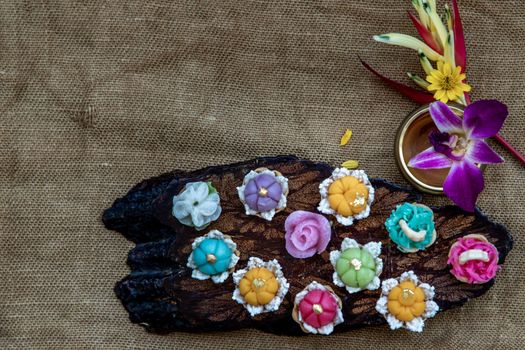 A variety of elegantly beautiful Thai Desserts (Khanom Wan Thai) colorful variations serving in a dark wooden, The bites in gold color and different flower shapes, Thai dessert, Auspicious dessert, Top view.
