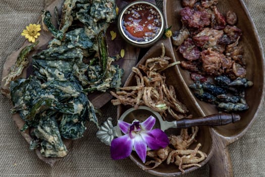 Close-up of Crispy Flowers, Crispy Herbs and Crispy Vegetables served  with Sweet sauce in a Wooden tray, copy space.