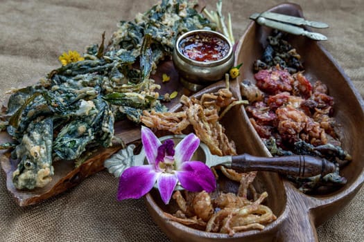 Crispy Flowers, Crispy Herbs and Crispy Vegetables served  with Sweet sauce in a Wooden tray, Oblique view from the top, copy space.