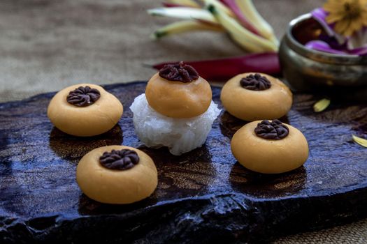 Traditional Thai Dessert (Kanom Thai) : Sanay Chan Made from minced coconut mixed with flour, sugar, egg yolk, rice flour and chan herb serving in a dark wooden, Oblique view from the top.