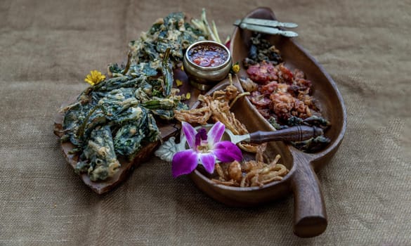 Crispy Flowers, Crispy Herbs and Crispy Vegetables served  with Sweet sauce in a Wooden tray, Oblique view from the top, copy space.
