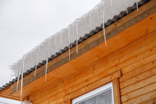 Spring ice icicles on roof of house. Patterns scattered by sun and frost. Selective focus