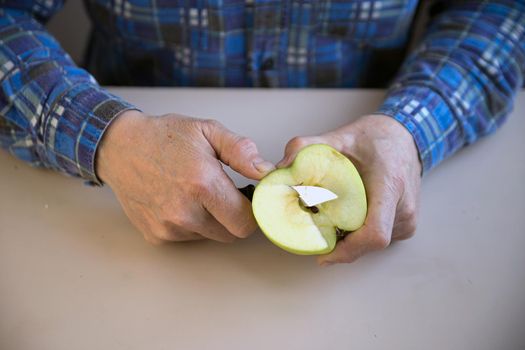 Man cuts apple with knife on slices.