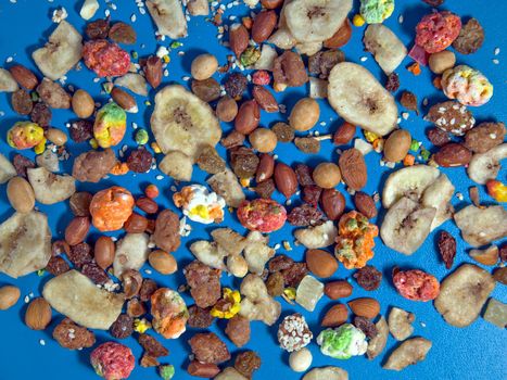 Colorful nuts are scattered on blue surface of table.