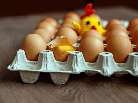 Brown chicken eggs and toy yellow chicken in gray box on table. Selective focus
