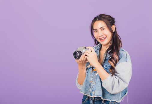 Portrait happy Asian beautiful young woman smiling excited wear denims holding vintage photo camera, teen female traveler female photographer, studio shot isolated on purple background