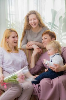 The kid congratulates mom and grandmother on the holiday, everyone hugs and laughs with happiness