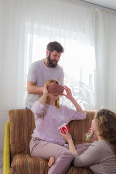 The family makes a surprise for mom, wishes her a happy holiday. Dad covered his mother's eyes with his palms.