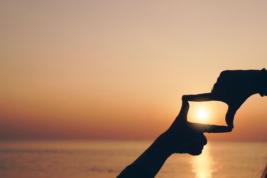 Selective focus of woman hands making frame by finger gesture with sunrise on mountain, Female capture sunrise or sunlight outdoor. Future planning concept.