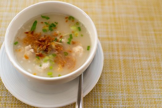 Thai style breakfast pork rice soup with egg on wood table. Copy space put your text on background.