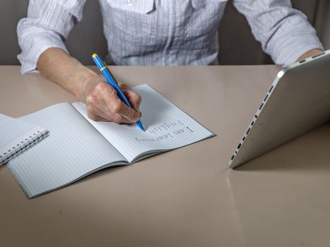 Notebook, hand with handle, tablet on light table. Online English language training.