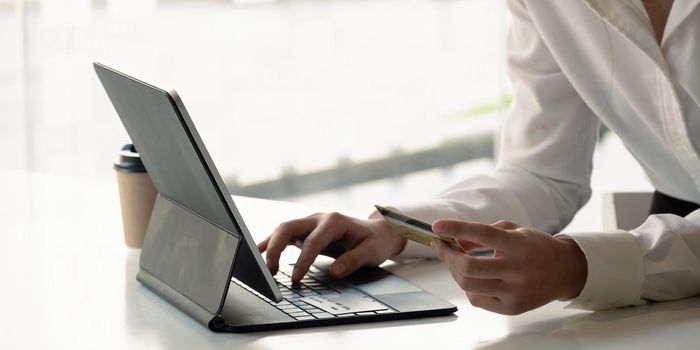 Close up girl makes a purchase on the Internet on the digital tablet with credit card at home.