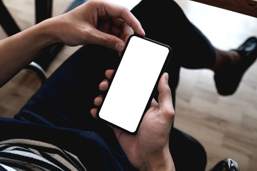 Top view male hand holding smartphone with blank screen at coffee shop.