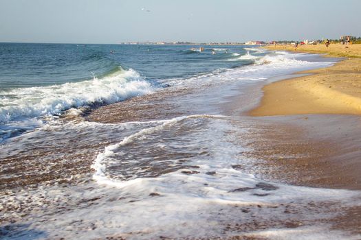 Sea coast with waves and people resting in the distance
