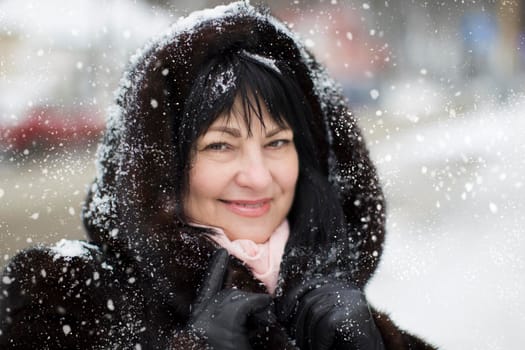 Elderly woman in a fur hood covered with snow