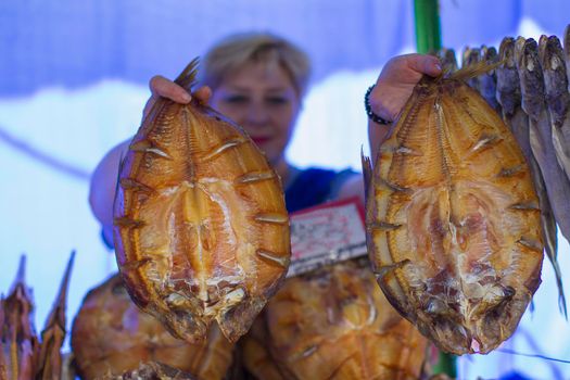 Chunks of dried fish at the fish market against the background of a blurred seller. Fish market