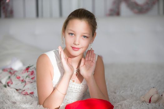 Very beautiful teen girl lying on a bed with a red heart pillow.Young lady