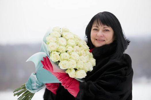 Luxurious elderly woman with a huge bouquet of flowers of roses on the street