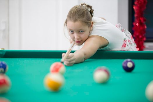 Girl playing billiards. Daughter playing pool