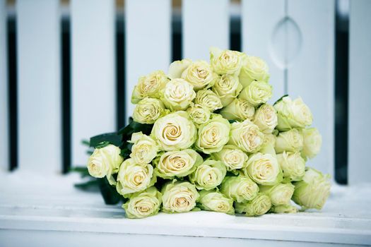 A bouquet of white roses on a white bench