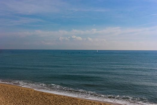 Barcelona beach in winter, with a calm sea and a cloudy blue sky