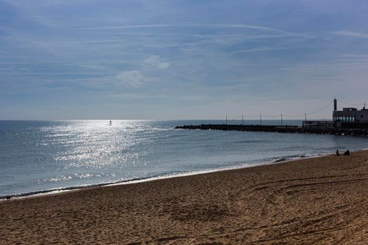 Barcelona beach in winter, with a calm sea and a cloudy blue sky